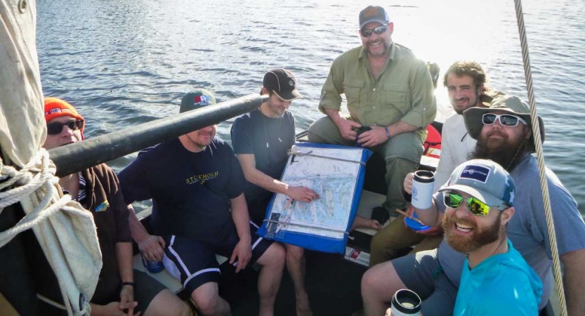 A group of veterans use a map to navigate on a sailing expedition.
